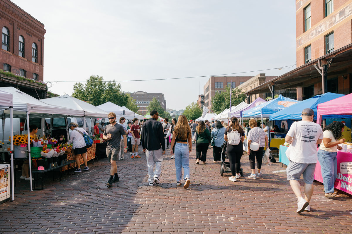 People strolling by booths at Omaha Farmers Market Old Market
